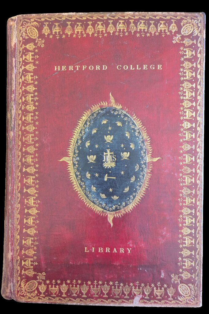 Front cover of book in re leather and gold decoration. Gold text reads Hertford College Library. In centre is a navy and gold decorative oval.