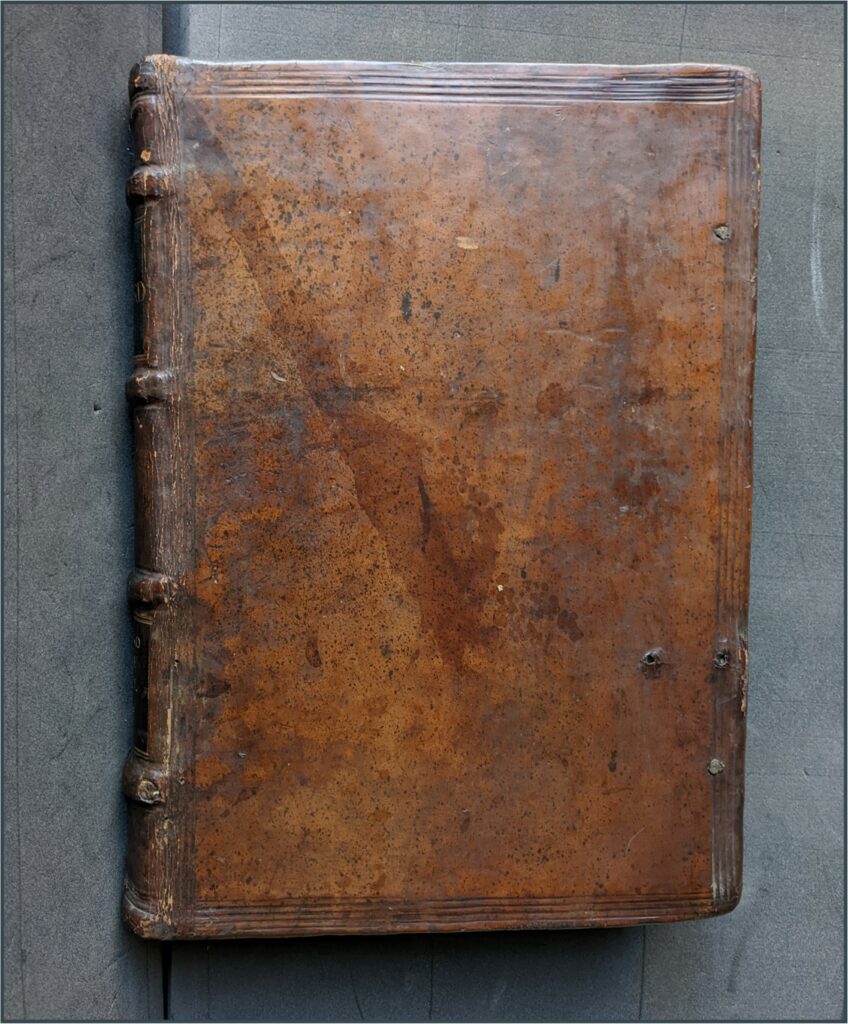 Front cover of book, with rough holes for chain marks near page edge