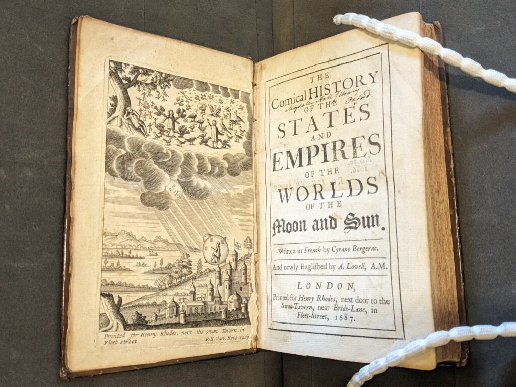 Book open to show printed title page and engraved title image of the Comical History. 