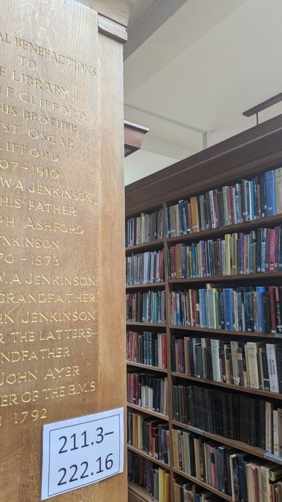 Close-up of shelves in Regent's Park Library. Gold inscription n a shelf-end in the foreground, with shelves full of books in the background.