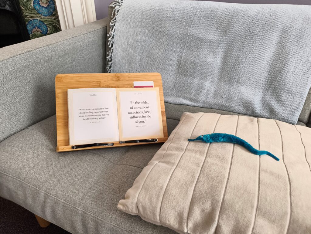 Worm on sofa on cushion looking at book with motivational phrases