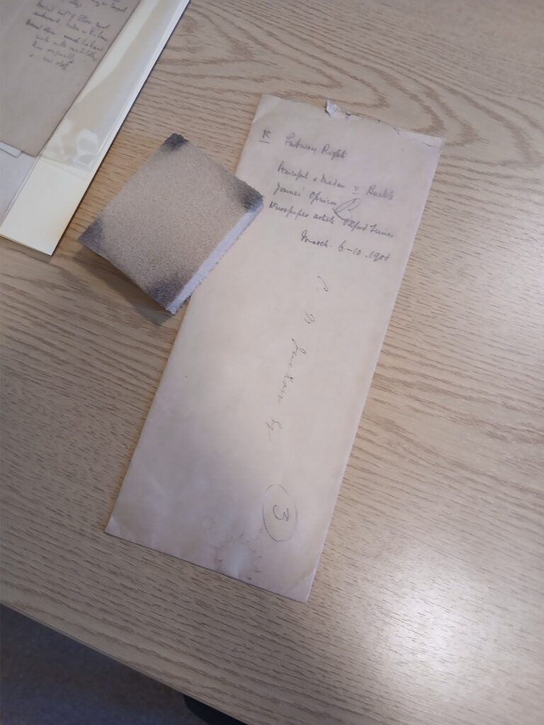 A cream envelope from the Victorian era with a cleaning sponge on a wooden desk